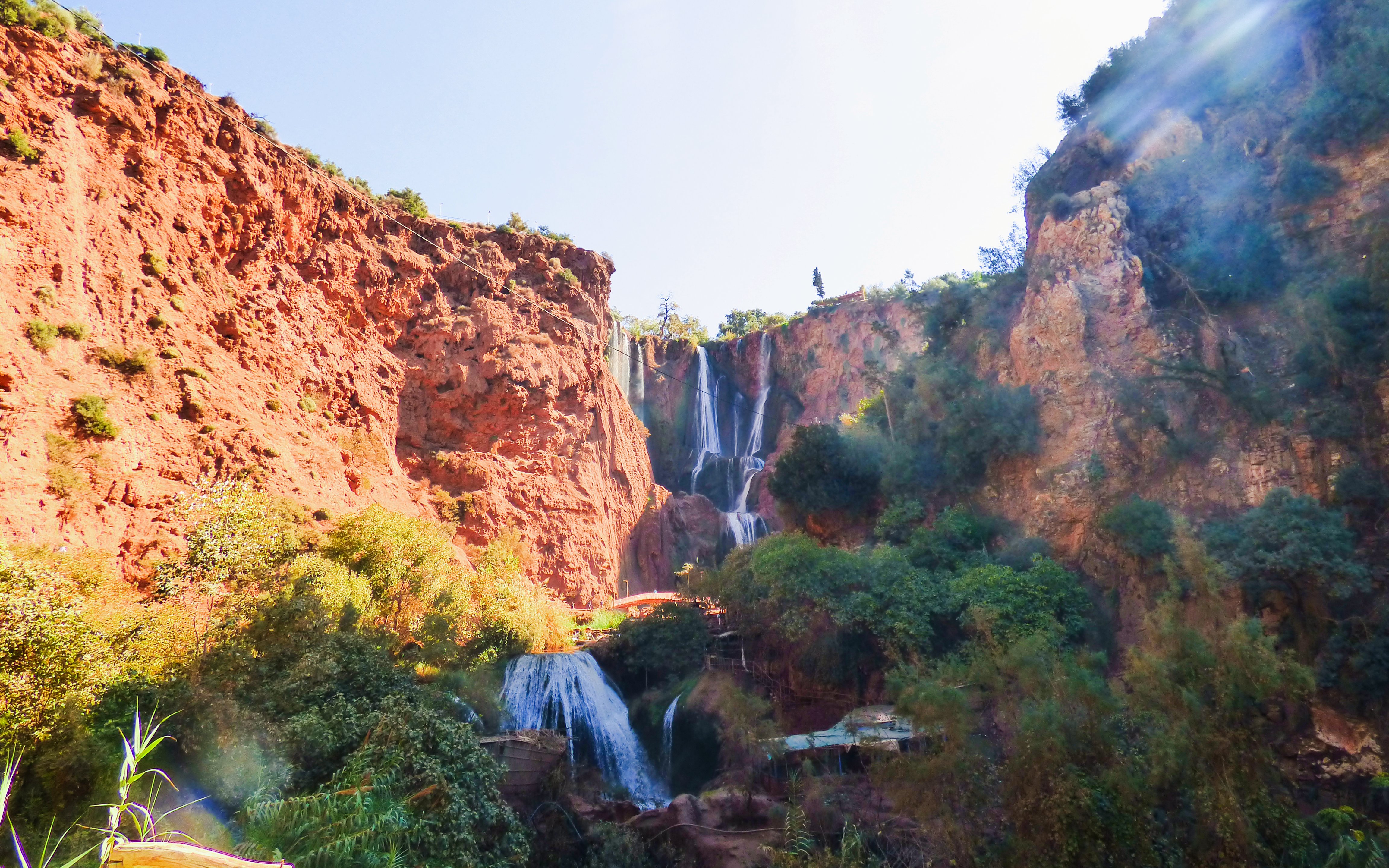 Ouzoud Waterfalls cascading down red cliffs surrounded by lush greenery in Morocco.