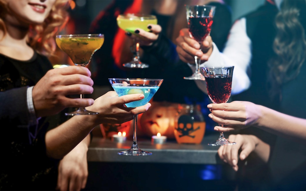 People toasting with colorful cocktails at a festive gathering.