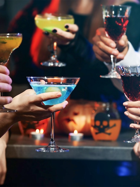 People toasting with colorful cocktails at a festive gathering.