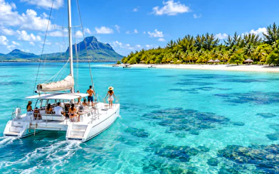 Catamaran sailing near Ile aux Cerfs with mountain view, Mauritius.
