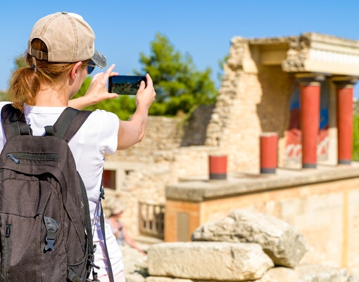 Tourist photographing ruins at Knossos Palace, Crete.