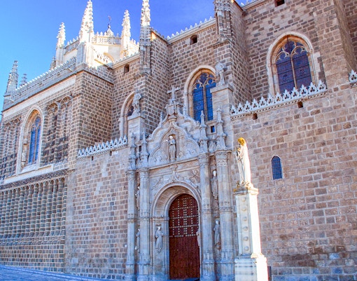 Monasterio de San Juan de los Reyes exterior with intricate Gothic architecture in Toledo, Spain.