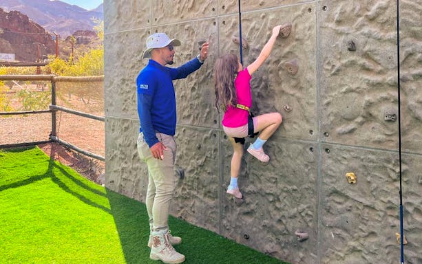 Child climbing wall with instructor at Hatta Wadi Hub, UAE.