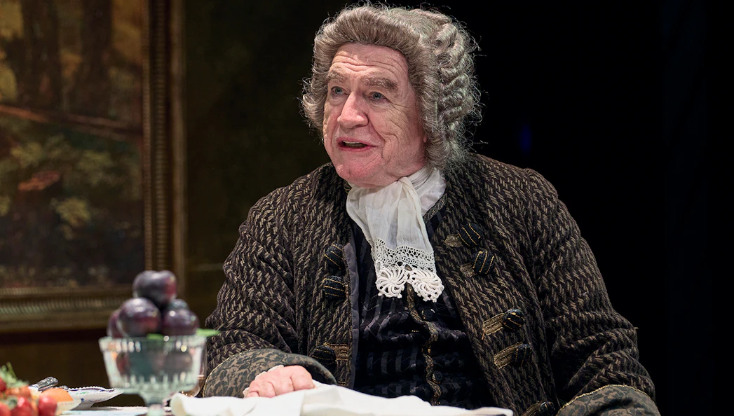 Actor in period costume seated at a table with fruit, related to The Score.