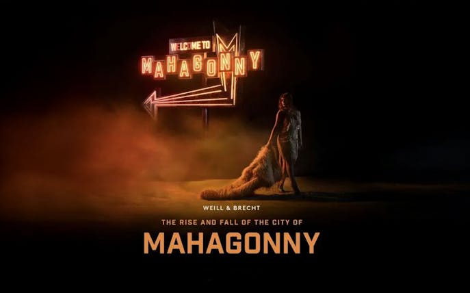 Stage set for "The Rise and Fall of The City of Mahagonny" opera performance, featuring dramatic lighting and urban backdrop.