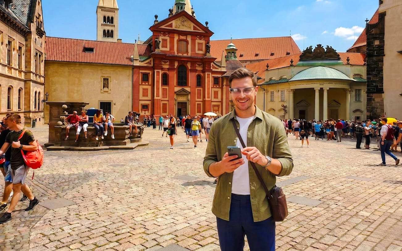 Guests using AR glasses at Prague Castle courtyard during Time Travel Tour.