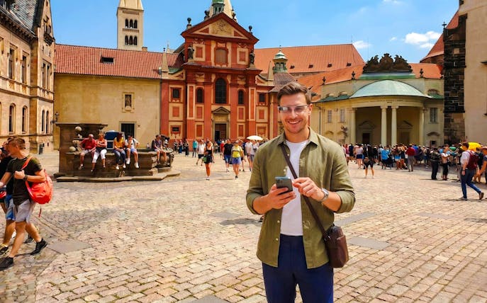 Guests using AR glasses at Prague Castle courtyard during Time Travel Tour.