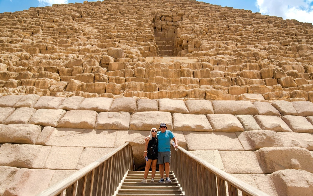 Couple standing on steps in front of Pyramid in Giza, Cairo day trip from Hurghada.