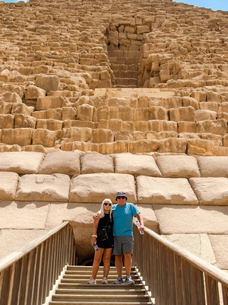 Couple standing on steps in front of Pyramid in Giza, Cairo day trip from Hurghada.