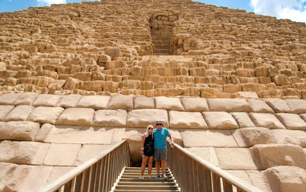 Couple standing on steps in front of Pyramid in Giza, Cairo day trip from Hurghada.