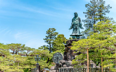 Statue surrounded by trees in a Japanese garden, Kansai-Hokuriku Area Pass.
