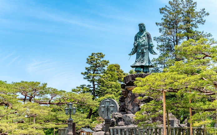 Statue surrounded by trees in a Japanese garden, Kansai-Hokuriku Area Pass.