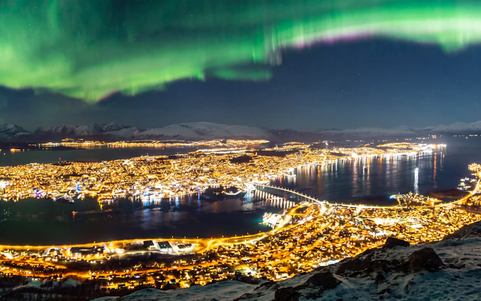 Night view of Tromsø city lights and Northern Lights from Fjellheisen.