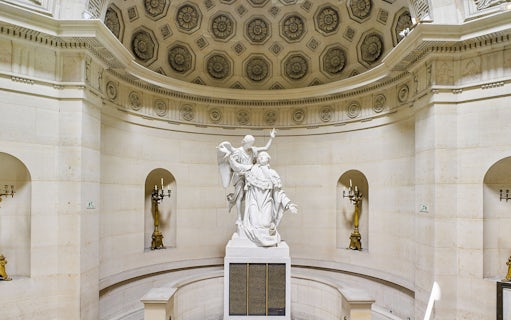 Statue inside Expiatory Chapel, Paris, with ornate ceiling and candelabras.