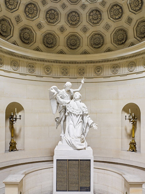 Statue inside Expiatory Chapel, Paris, with ornate ceiling and candelabras.