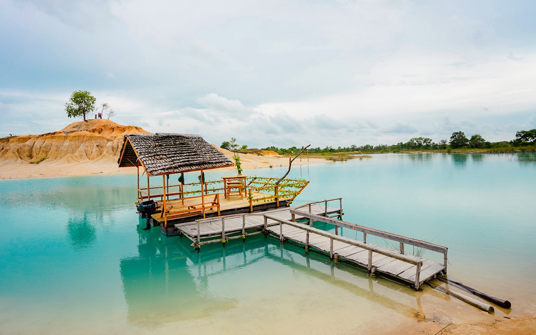 Wooden boat docked on Blue Lake near Bintan Mini Desert, Indonesia.