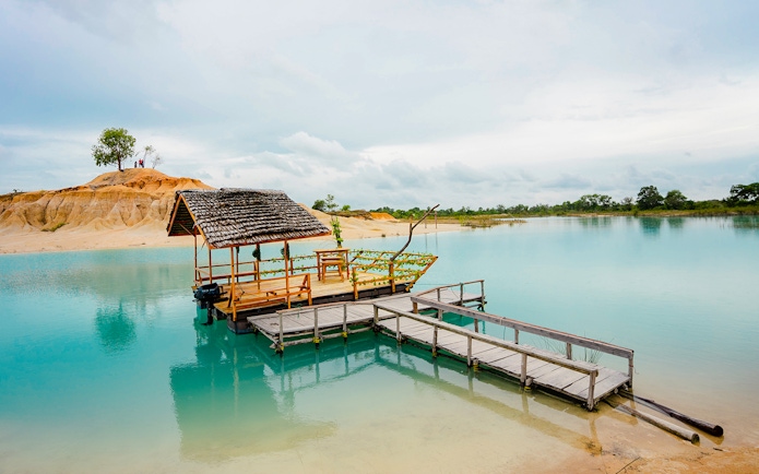 Wooden boat docked on Blue Lake near Bintan Mini Desert, Indonesia.