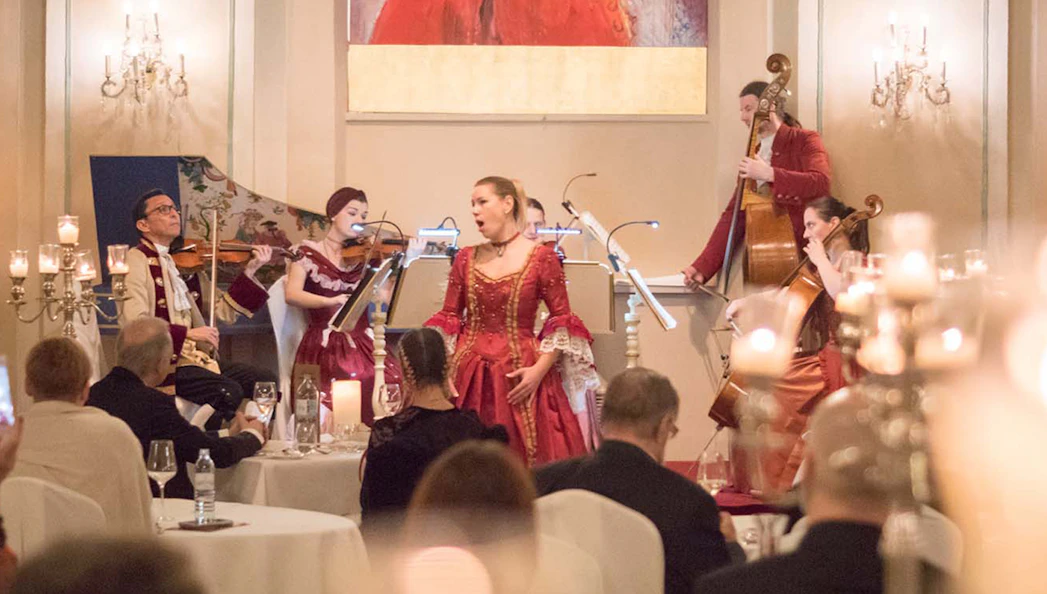 Musicians in period costumes perform at a Mozart concert in a historic Salzburg venue.