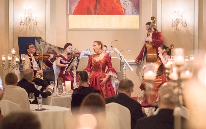 Musicians in period costumes perform at a Mozart concert in a historic Salzburg venue.