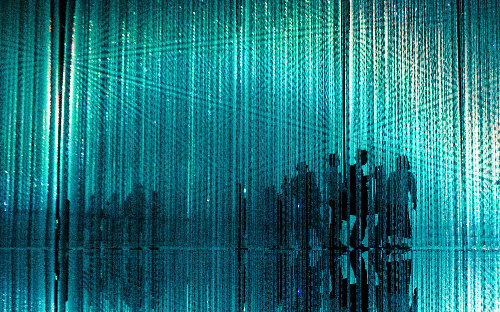 Visitors walking through immersive abstract art installation with blue light.