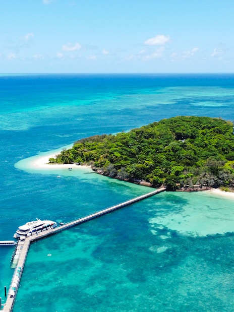 Catamaran docked at Green Island, surrounded by coral reef and turquoise waters.
