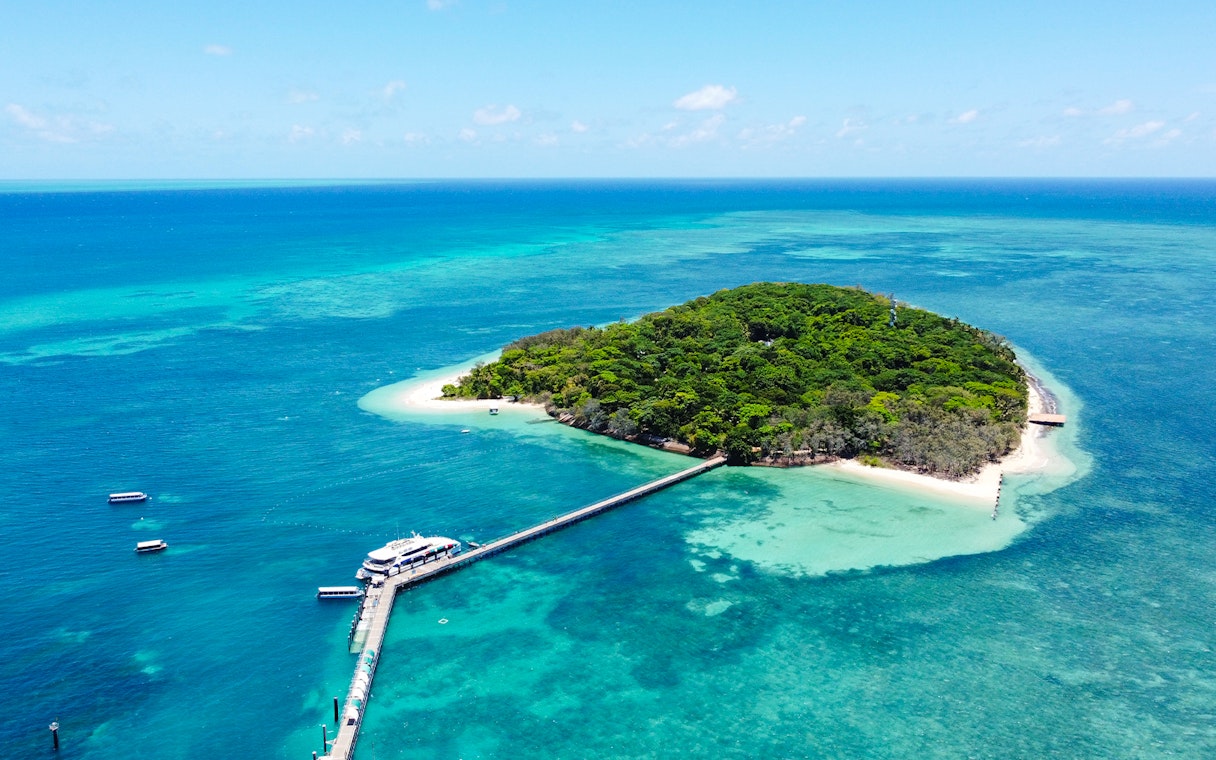 Catamaran docked at Green Island, surrounded by coral reef and turquoise waters.