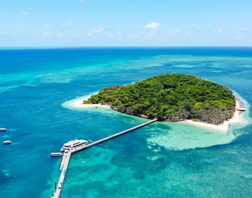Catamaran docked at Green Island, surrounded by coral reef and turquoise waters.