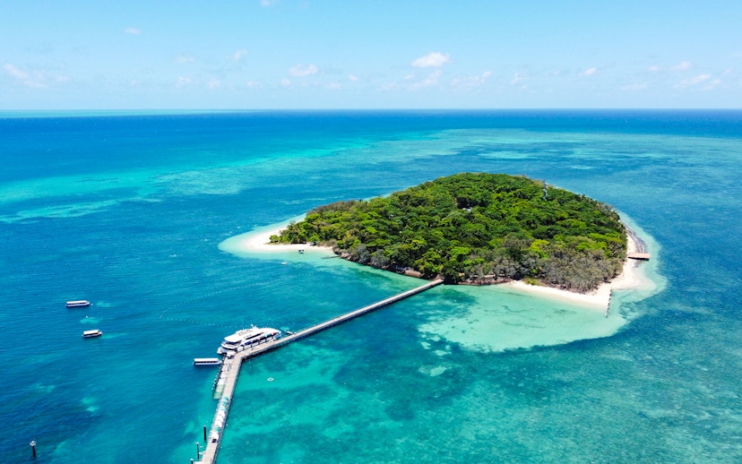 Catamaran docked at Green Island, surrounded by coral reef and turquoise waters.