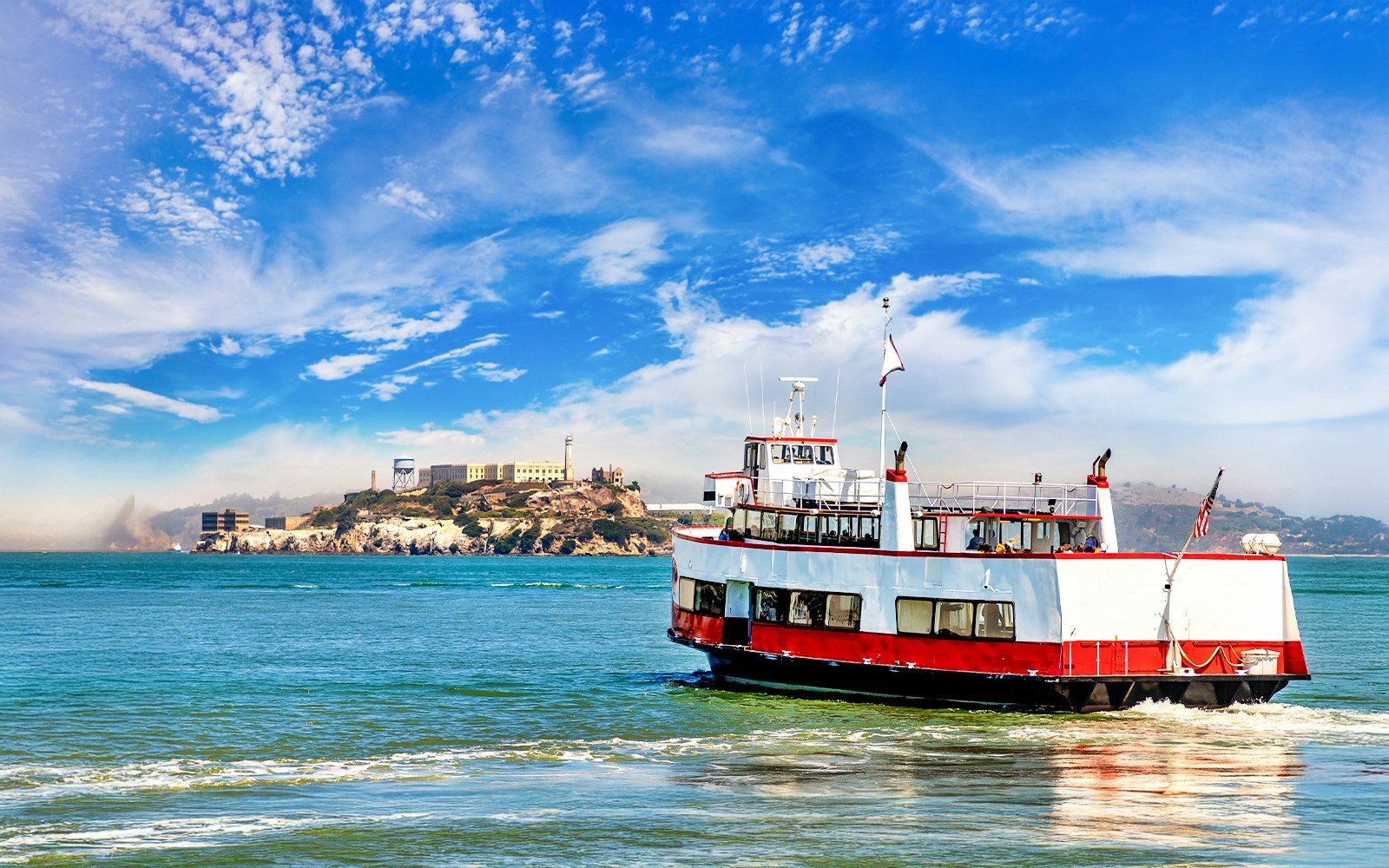 Ferry approaching Alcatraz Island with tourists in San Francisco Bay, California.