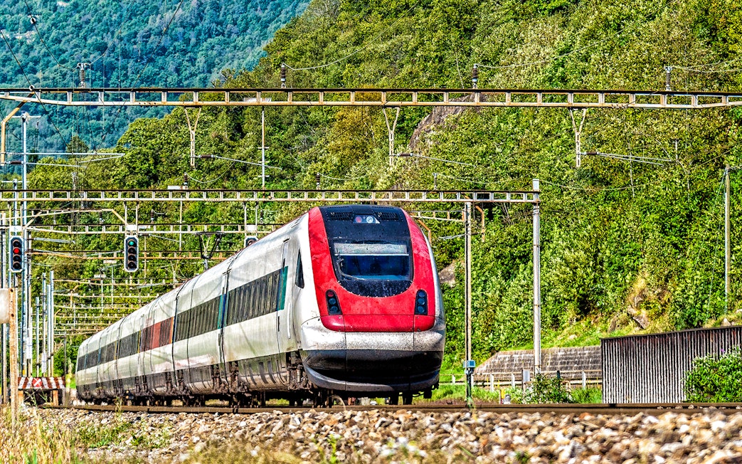 Train traveling through lush landscape, Geneva Airport to Geneva Train Station.