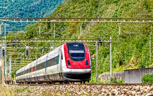 Train traveling through lush landscape, Geneva Airport to Geneva Train Station.
