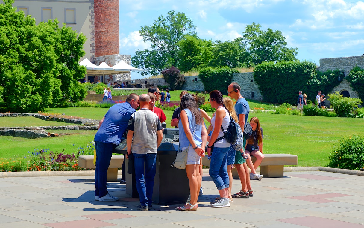 Visitors gather around a guide at Wawel Cathedral, Krakow, during a tour.