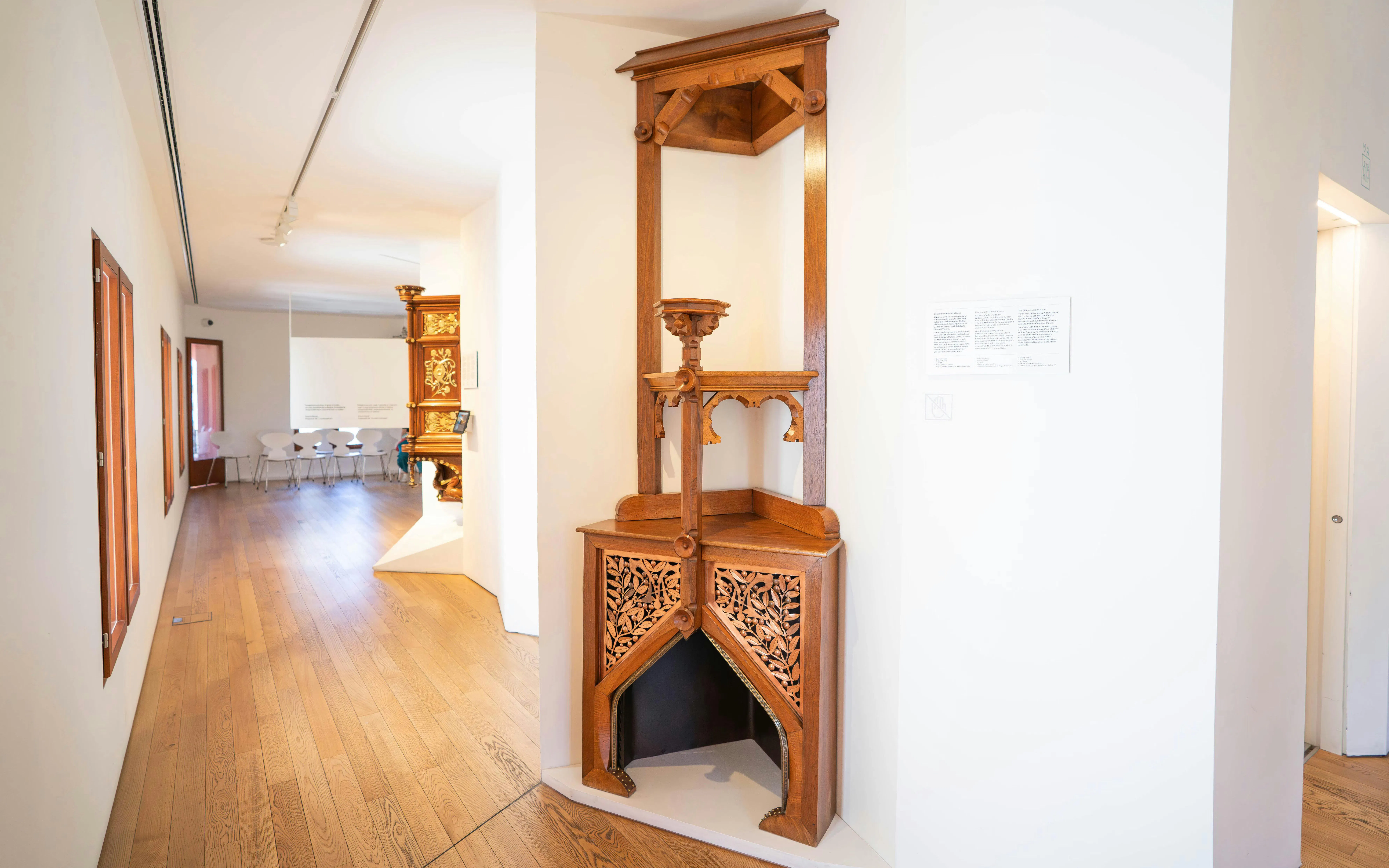Casa Vicens wooden corner table exhibit in Barcelona museum hallway.