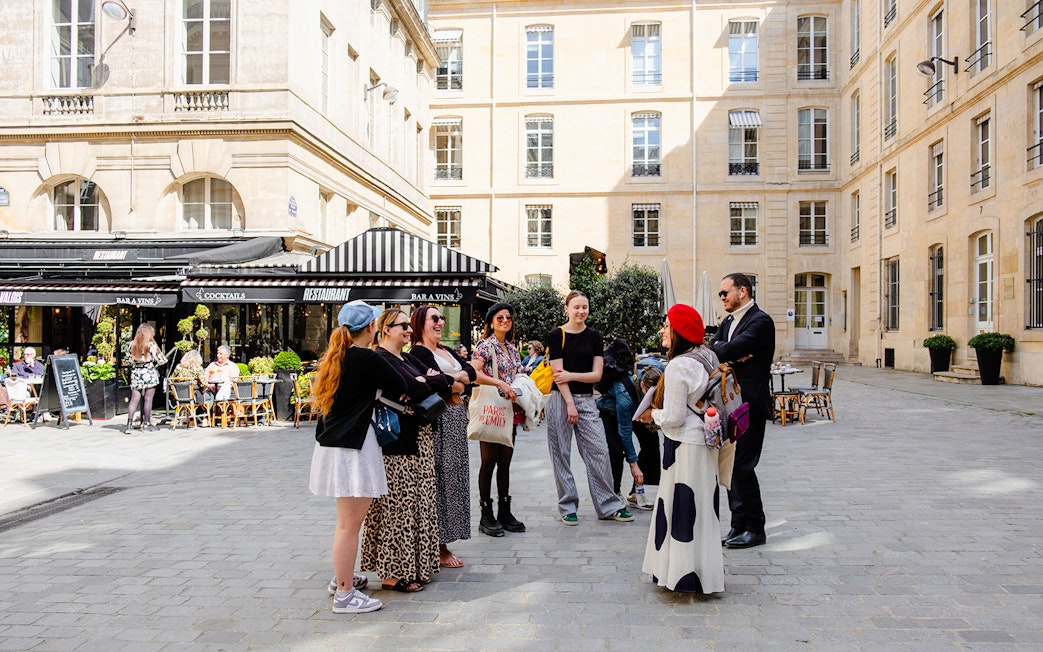 Tour guide with tourists on Emily in Paris Locations Walking Tour in Paris courtyard.