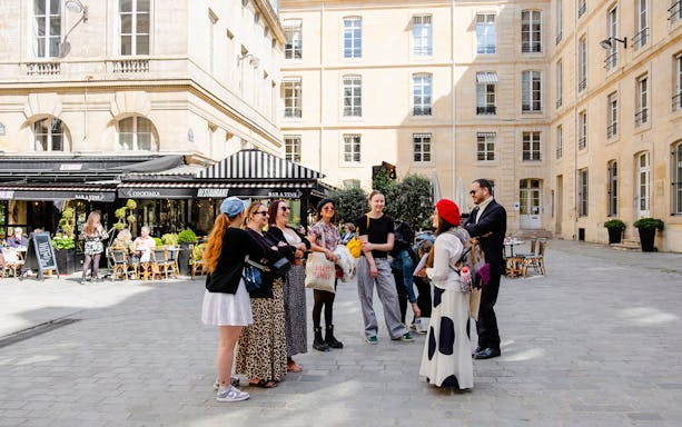 Tour guide with tourists on Emily in Paris Locations Walking Tour in Paris courtyard.
