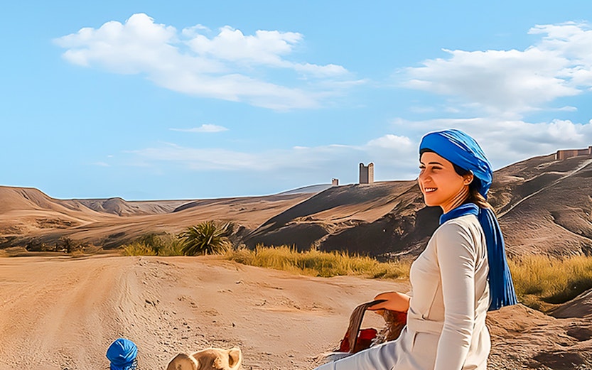 Woman riding camel in Agafay Desert, Marrakech with guide leading.