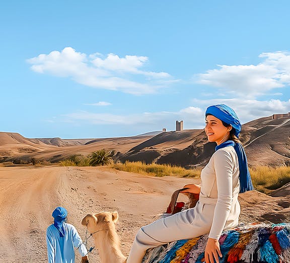 Woman riding camel in Agafay Desert, Marrakech with guide leading.