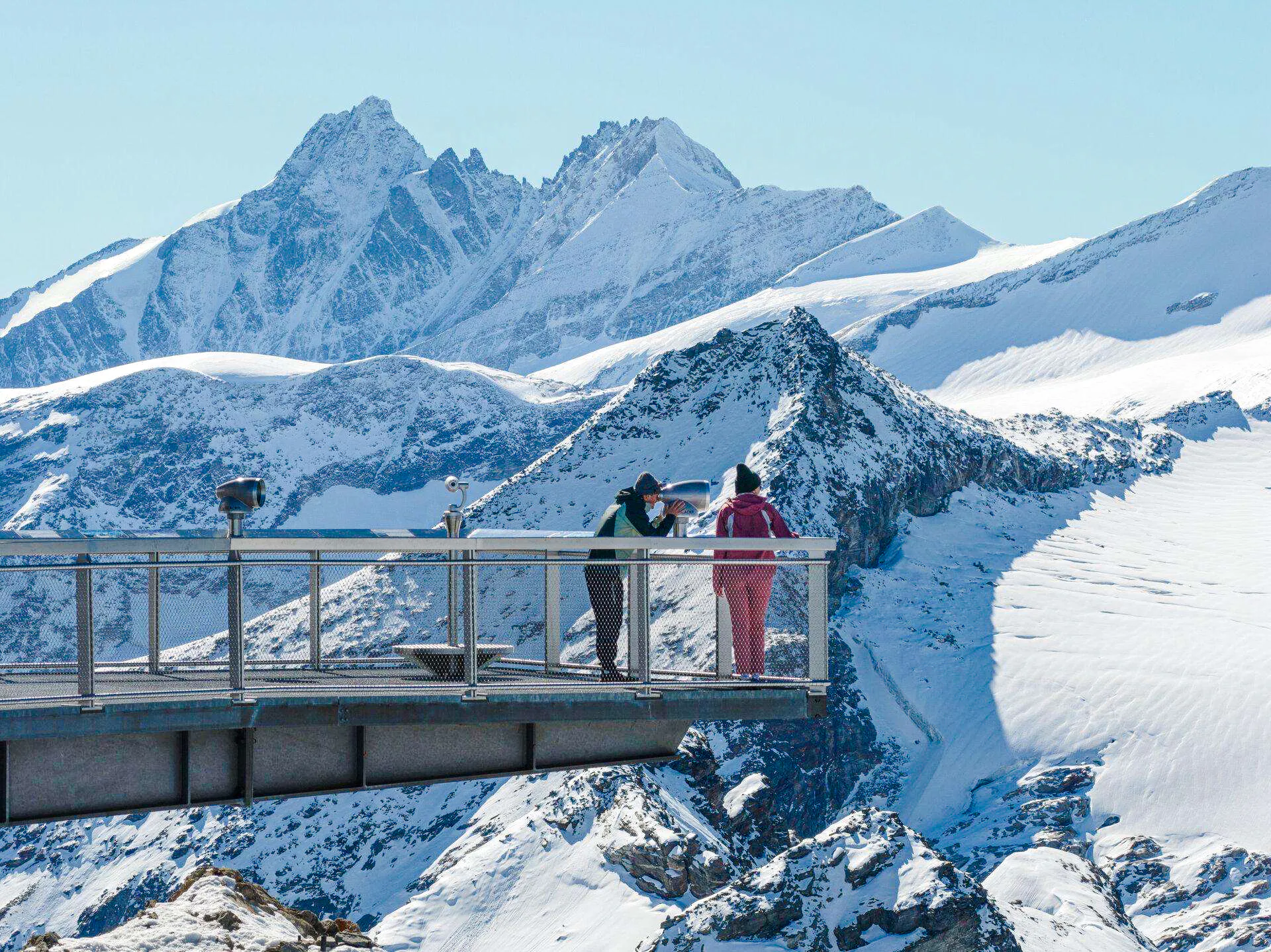 Visitors on a viewing platform overlooking snowy peaks at Kitzsteinhorn, Salzburg.