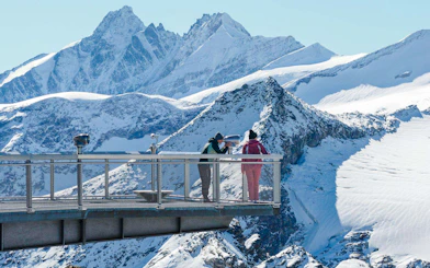 Visitors on a viewing platform overlooking snowy peaks at Kitzsteinhorn, Salzburg.