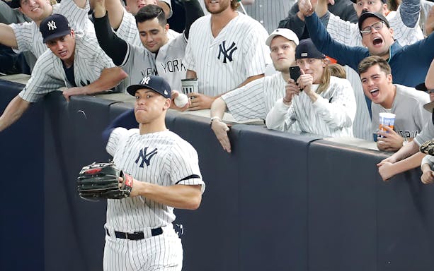 New York Yankees player catching a ball near fans during a game against Arizona Diamondbacks.
