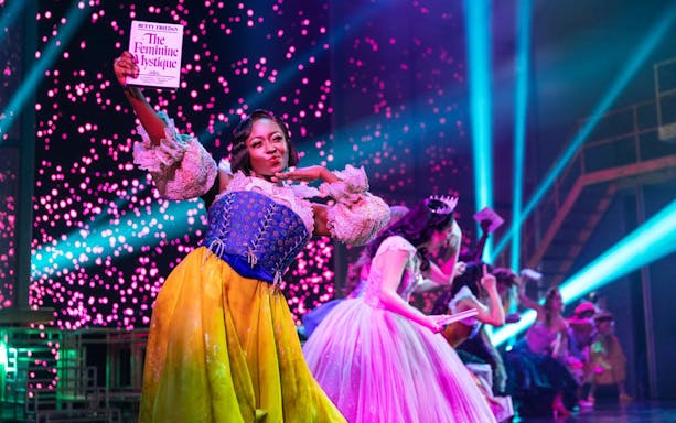 Performer on stage holding a book during "Once Upon a One More Time" show.