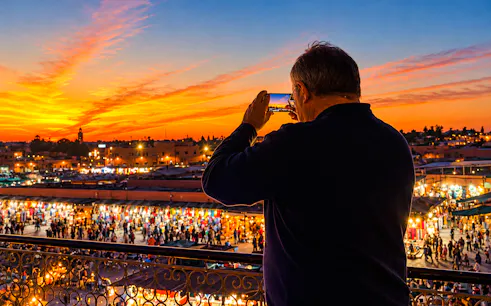 Marrakech rooftop view of Jemaa el-Fna at sunset with bustling market below.