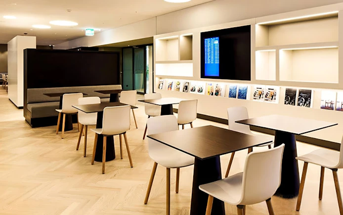 Seating area in Aspire ONE Lounge at Zurich Airport with tables and chairs.