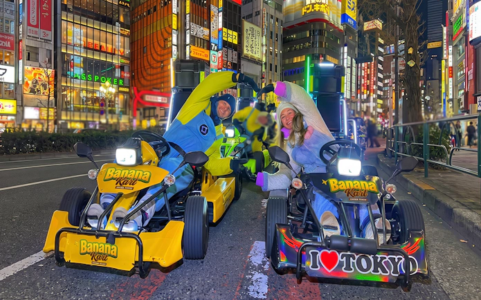 Go-kart riders in costumes on Banana Kart tour, Shinjuku to Shibuya, Tokyo at night.