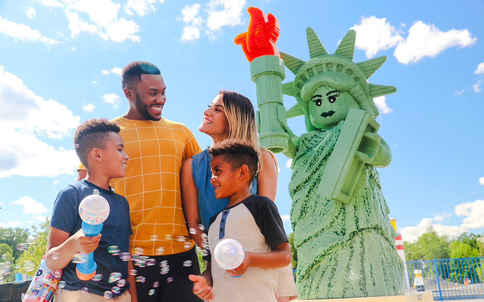 Family enjoying time near Lego Statue of Liberty at Legoland, New York.