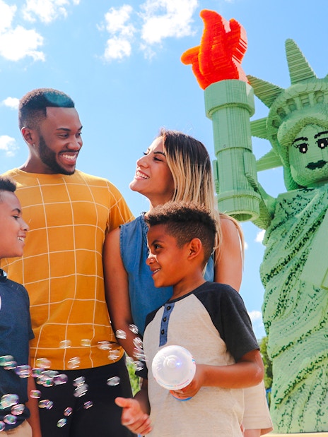 Family enjoying time near Lego Statue of Liberty at Legoland, New York.