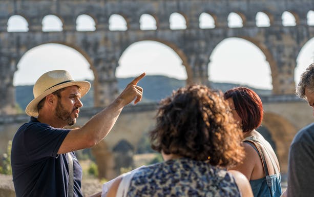 Tour guide explaining Pont du Gard to visitors in Provence.