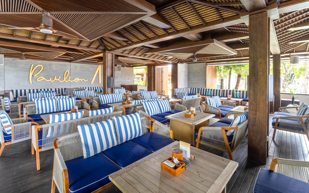 Atlas Beach Club seating area with striped cushions and wooden tables.