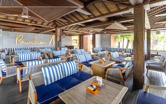 Atlas Beach Club seating area with striped cushions and wooden tables.