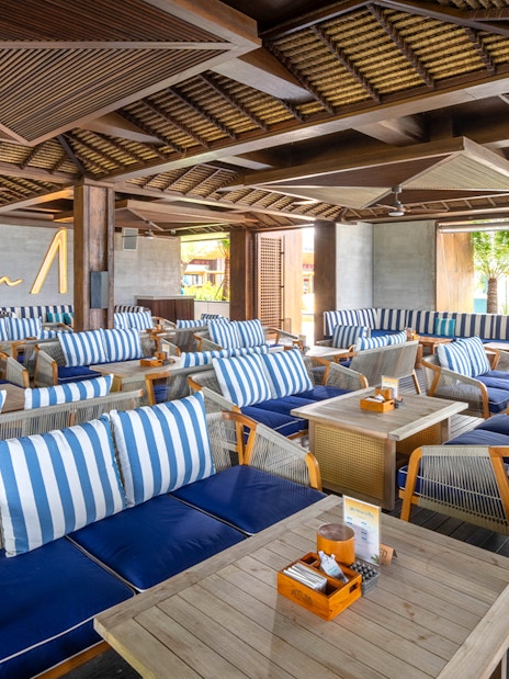 Atlas Beach Club seating area with striped cushions and wooden tables.